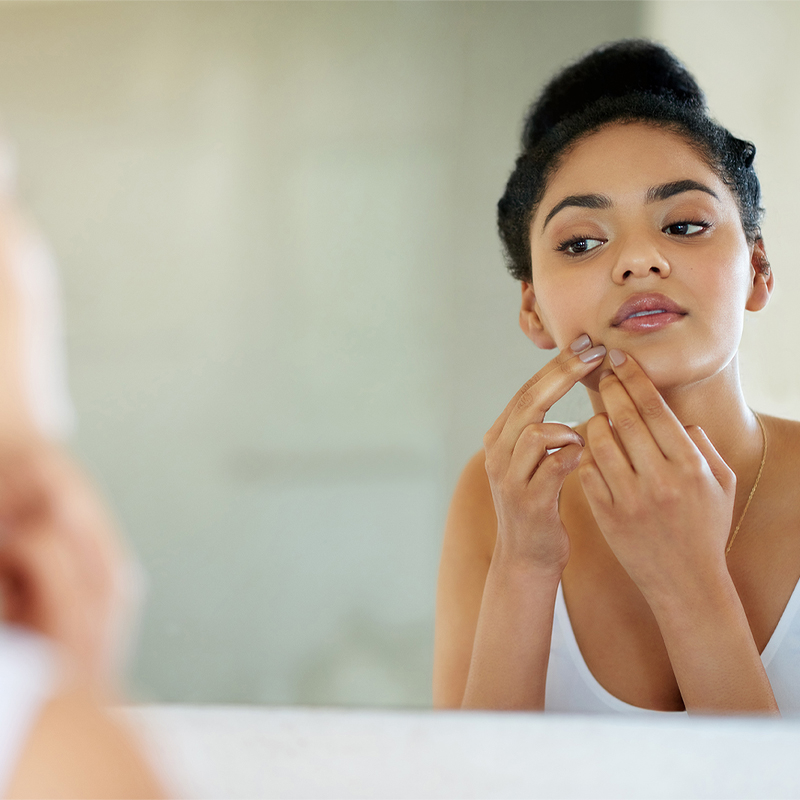 teenager with pimples in front of the mirror